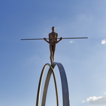 Sculpture Balance by the artist Martina Ondáková in front of a blue sky, human figure balanced,