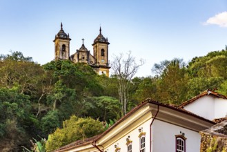 Historic buildings and a baroque church amidst the vegetation of the hills of the city of Ouro