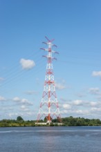 An extremely high electricity electricity electricity pylon, marked white and red, stands on the