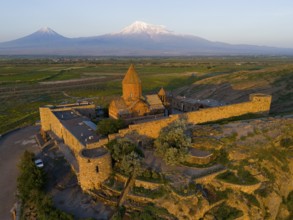 Monastery in the light of the sunrise with mountains in the background and peaceful nature, aerial