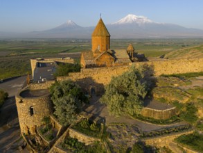 Historic church with stone walls in front of a mountain landscape with blue sky, aerial view, Chor