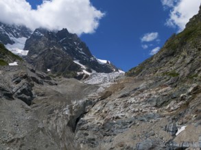Impressive glacier landscape with rocks and mountains dominated by a clear blue sky and clouds,