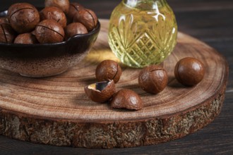 Bottle of macadamia oil, on a wooden board, with macadamia nuts, wooden background, selective