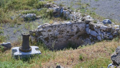 Ancient ruins with preserved column on a stone block in the surroundings of a historical site,