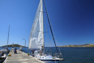 A sailing boat moors in sunny weather at a pier in the deep blue sea, Analipsi, Maltezana,