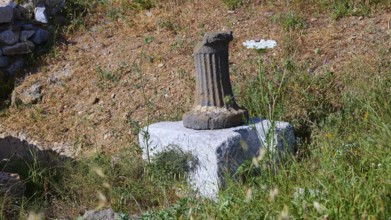 An old column on a pedestal surrounded by grass at a historical site, ancient Roman bath, Tallaras,