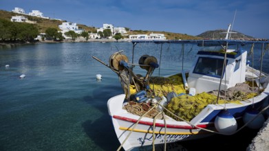 A fishing boat in the calm waters of a harbour with white buildings in the background, Analipsi,
