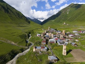 A picturesque village with historic buildings and towers in a green valley between mountains,