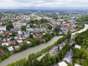 Urban panoramic view with river surrounded by dense residential areas and green trees under a