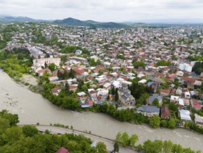 Overview of a hilly cityscape with river, residential buildings and a prominent church, aerial