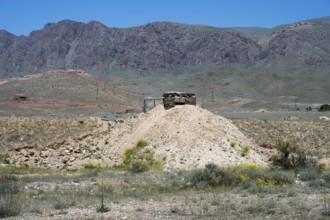 Abandoned-looking bunker on a hill in a mountainous landscape, embrasure on the border to the