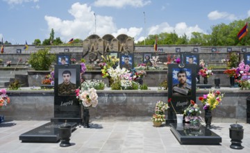 Row of decorated tombstones with portraits and flowers, Armenian flag visible, graves of 2020,