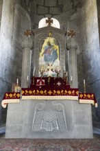Church altar with religious symbols and icon, decorated with red cloths and candles, Sisian,