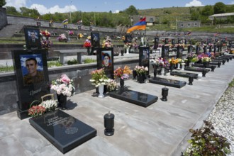 Graves in rows with portraits and flowers, Armenian flag in the background, graves of 2020, victims