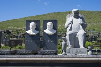 Stone busts and figure on a cemetery in front of a green hill and blue sky, Gyumri, Alexandropol,