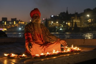 Sadhu on boat, burning candles, Mughalsarai, Uttar Pradesh, India