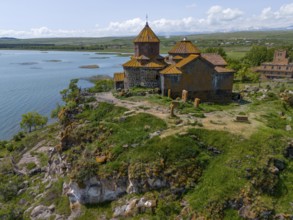 Church on a rocky outcrop, surrounded by lush greenery, overlooking a tranquil lake, aerial view,