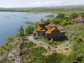 Historic church on the shore of a lake, surrounded by lush nature and clear skies, aerial view,