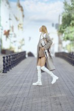 Stylish woman in a long coat and knee-high boots strolls confidently cross a charming cobblestone