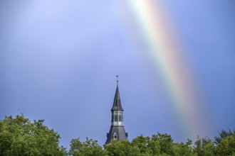 Colourful rainbow over trees and castle tower after downpour during thunderstorm in summer