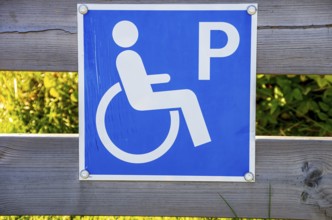 Sign with pictogram Car park for the disabled on a wooden fence, near Henan on Orust, Bohuslän,
