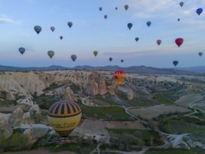 Aerial view of balloons over a vast landscape at sunrise in Cappadocia, aerial view, Göreme