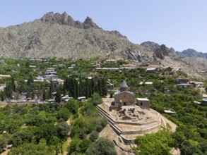 Small historic church on a hill with mountains in the background and lush vegetation, aerial view,