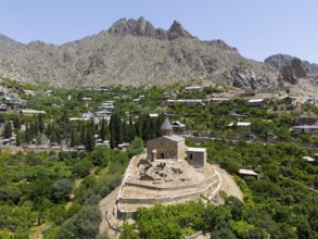 Historic mountain church surrounded by lush vegetation and impressive mountains, aerial view, St