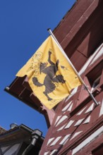 Cantonal flag of Schaffhausen on a half-timbered house, pictogram of a black goat striding freely