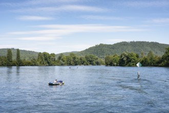 Inflatable boat, stand up paddler, swimming next to a fairway on the Rhine, Hochrhein near