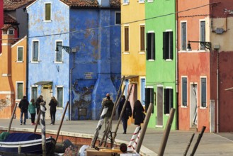 Strollers along the canal, typical street scene in winter, colourful facades in Burano, island in