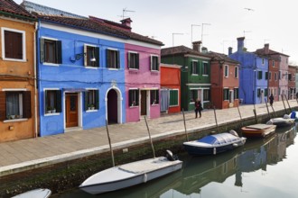 Lone walkers on the canal, typical street scene in winter, colourful facades in Burano, island in