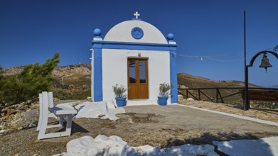 White chapel with blue façade and cross in an open, mountainous landscape, Panagia tou Paleokastro,