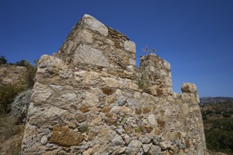 Old stone ruins in a Mediterranean landscape under a clear sky with sparse vegetation, Panagia tou