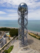 Modern tower by the sea with a view of the coast and the beach under a blue sky, aerial view,