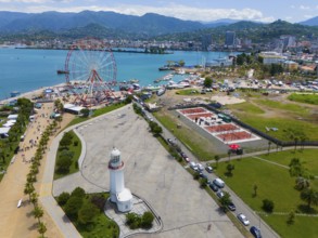 Aerial view of a harbour area with Ferris wheel, lighthouse and town by the sea, surrounded by