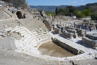 Ancient stone amphitheatre with steps surrounded by ruins in a historical site, theatre, Efes,