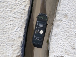 Car driving between high snow walls on a narrow road, seen from above, aerial view, camper,