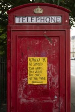 Red London telephone box with yellow poster, Kensington, London, England, Great Britain