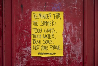 Yellow poster on phone box reminds people to appreciate nature and put their mobile phones away,