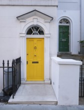 Bright yellow front door with neoclassical triangular pediment, Palladian-style entrance, white