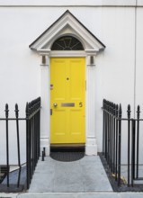 Bright yellow front door with house number five and neoclassical triangular gable, Palladian-style