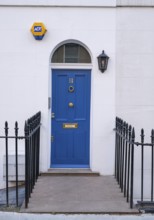 Blue door with house number 11 flanked by a lantern and a security sign, surrounded by a wrought