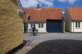 Cyclist on sunny street with colourful brick houses, Old Town, Ringkøbing, Ringkøbing Fjord,