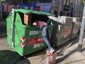 Poverty in Buenos Aires, a homeless man searches for something usable in a rubbish container,