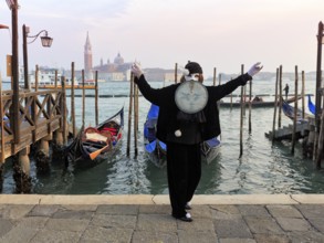 Person with black costume and mask, full moon mask, boat dock at St Mark's Square, behind the