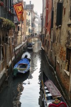 Strollers on a small bridge, boats on a canal, typical street scene in Venice, Italy