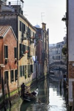 Gondola in winter, gondoliers on a canal, typical street scene in Venice, Italy