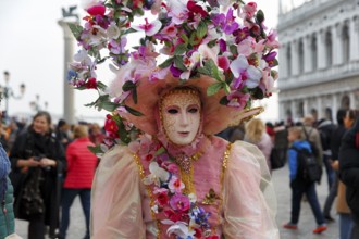 Venetian mask, disguised woman with big hat, walker, crowd on St Mark's Square, Carnival in Venice,