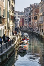 Walkers in winter, boats on canal, typical street scene in Venice, Italy